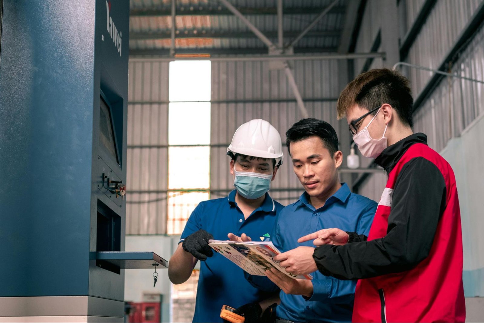 A manager speaking to two workers at a factory